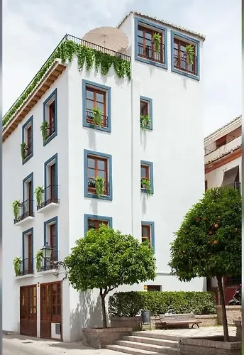 Fachada de Sueño de Elvira en Calle Elvira: cal blanca, carpintería azul y naranjos